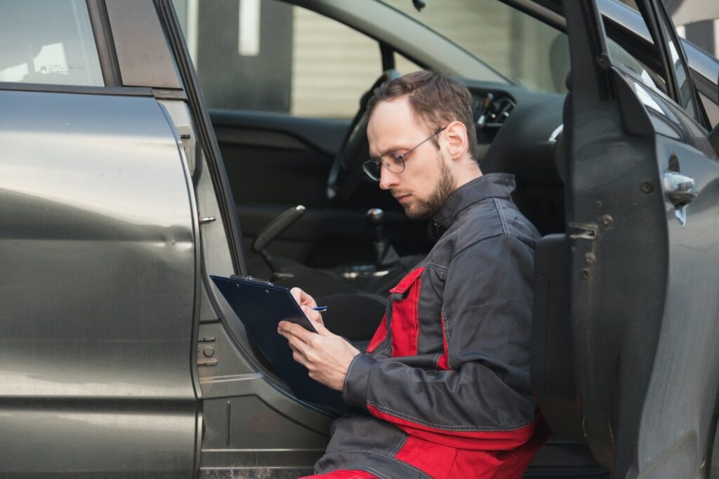 the mechanic checks the door and checks the VIN code of the car, makes notes